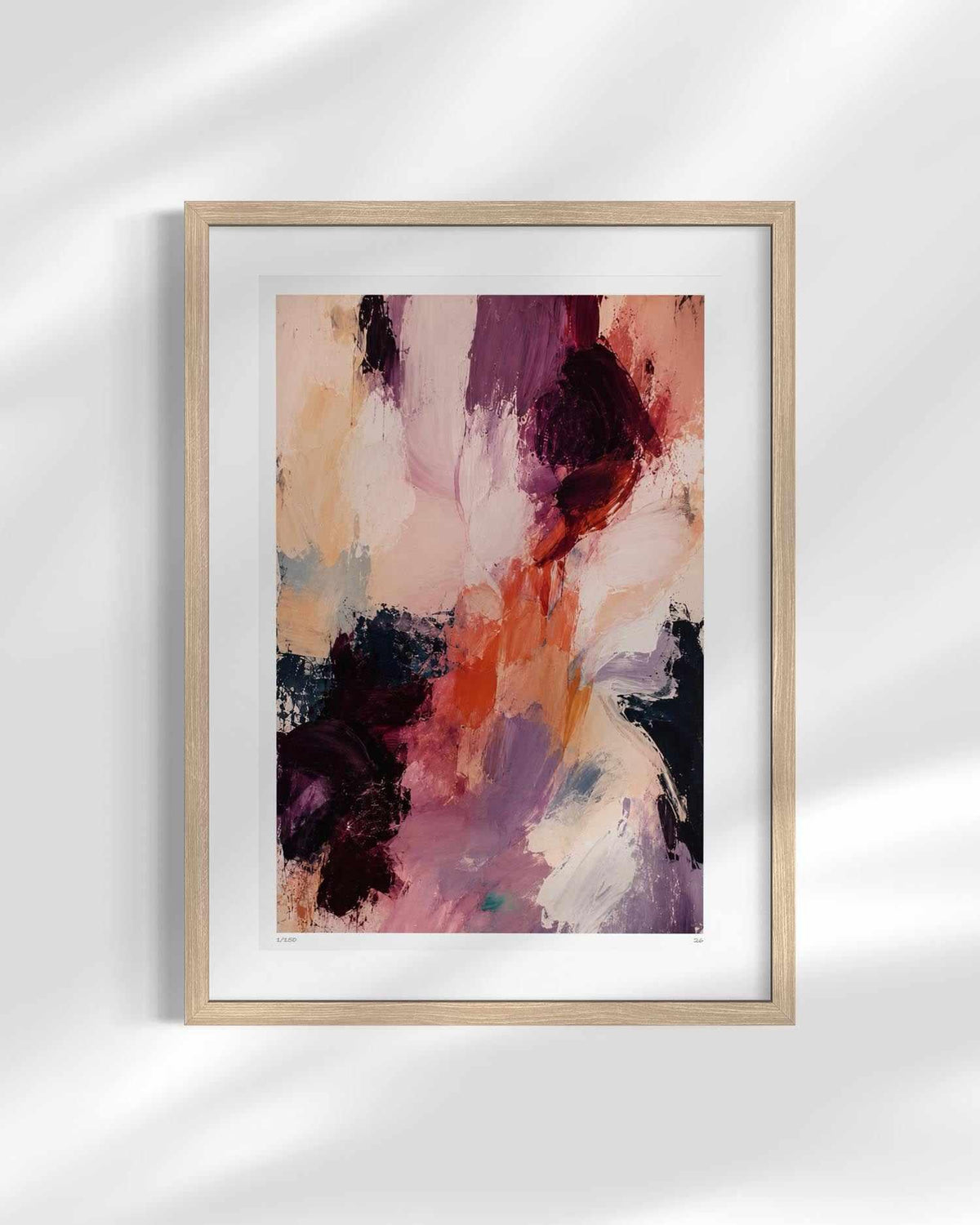Framed abstract wall art featuring expressive brushstrokes in pink, purple, peach, orange, and dark plum tones, displayed in a light wood frame with a white mat against a softly lit wall.