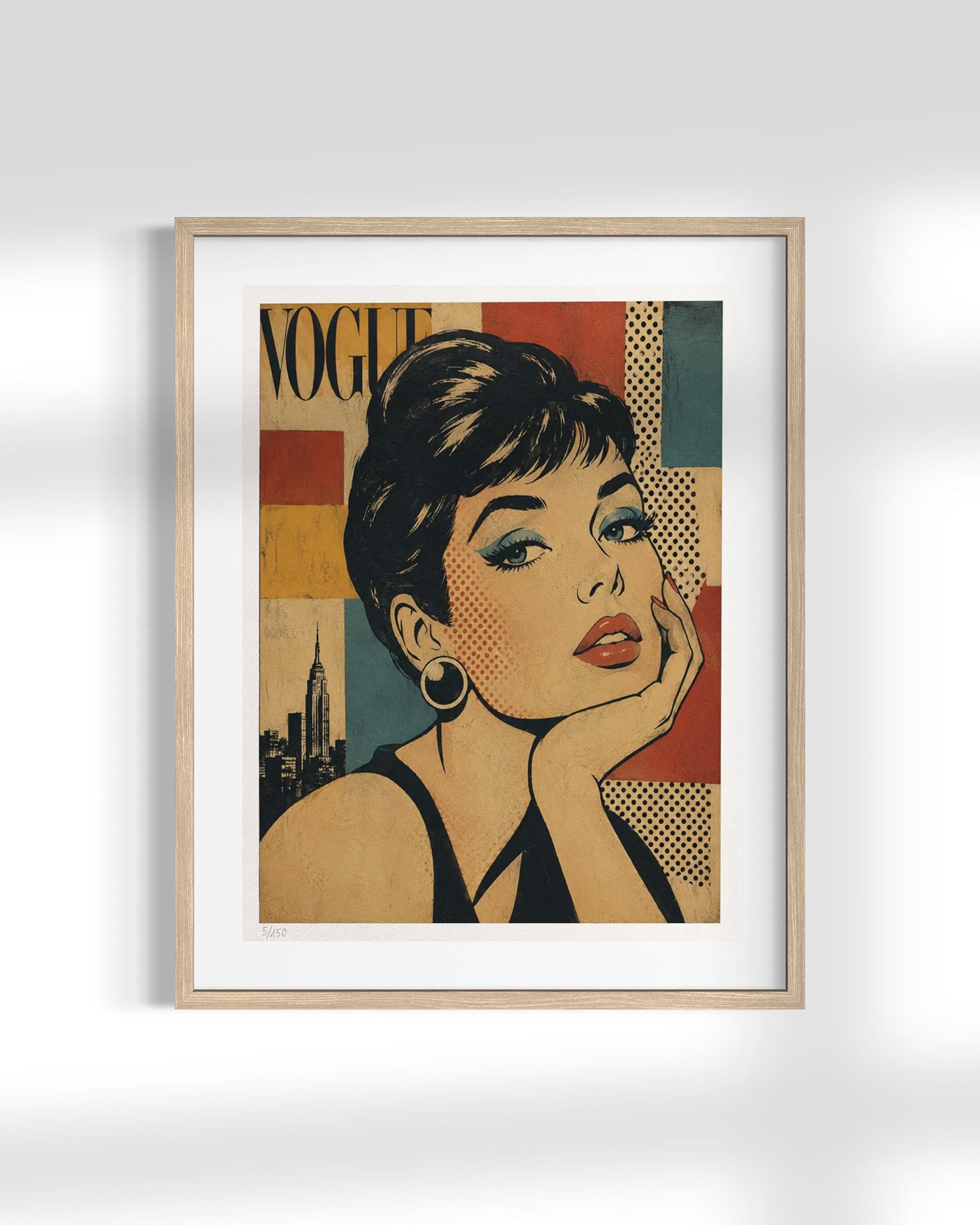 A framed art print featuring a stylized pop-art portrait of Audrey Hepburn in a Vogue-inspired design, displayed on a light gray wall with soft shadows.