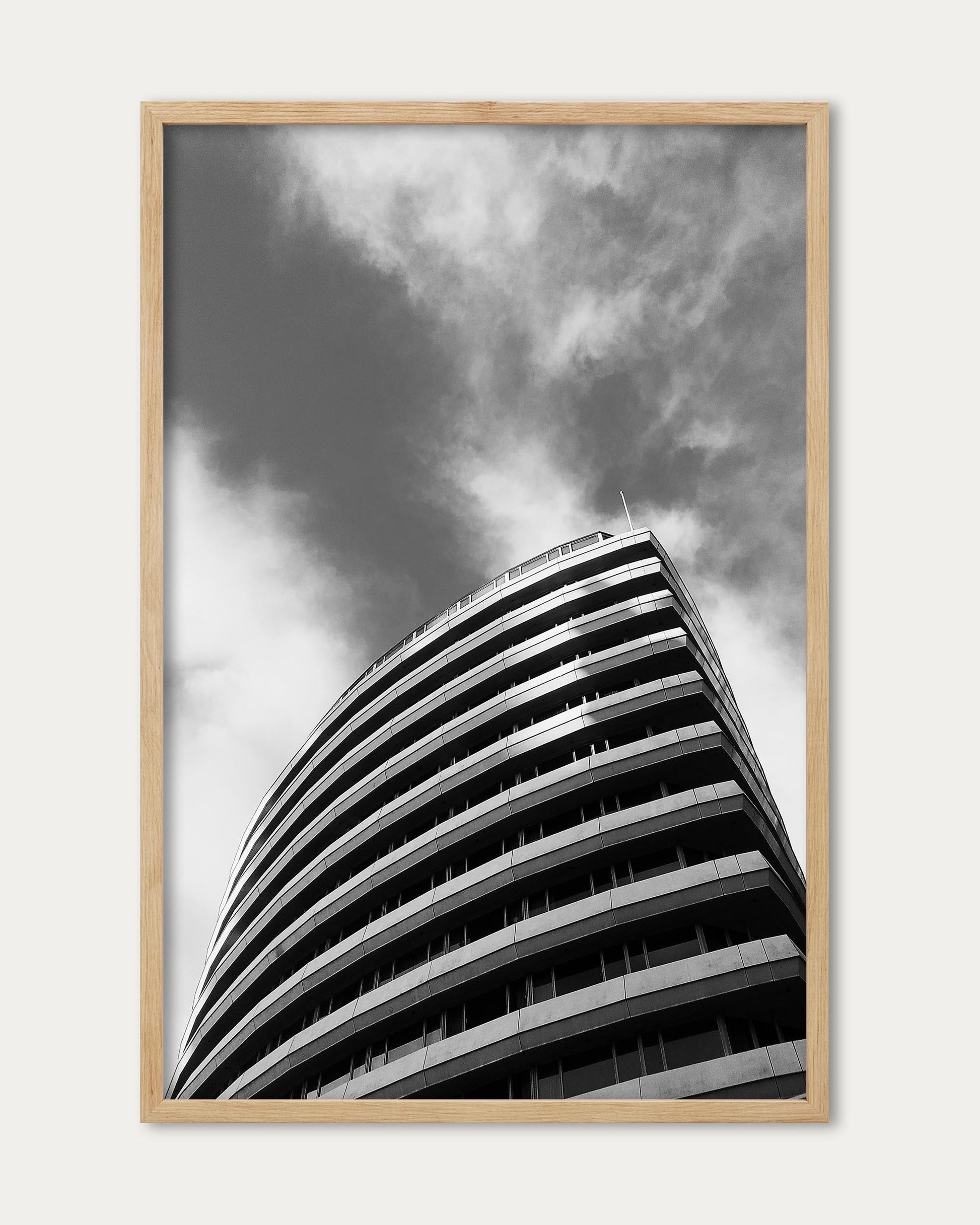 Framed black and white photograph of a modern building against a cloudy sky