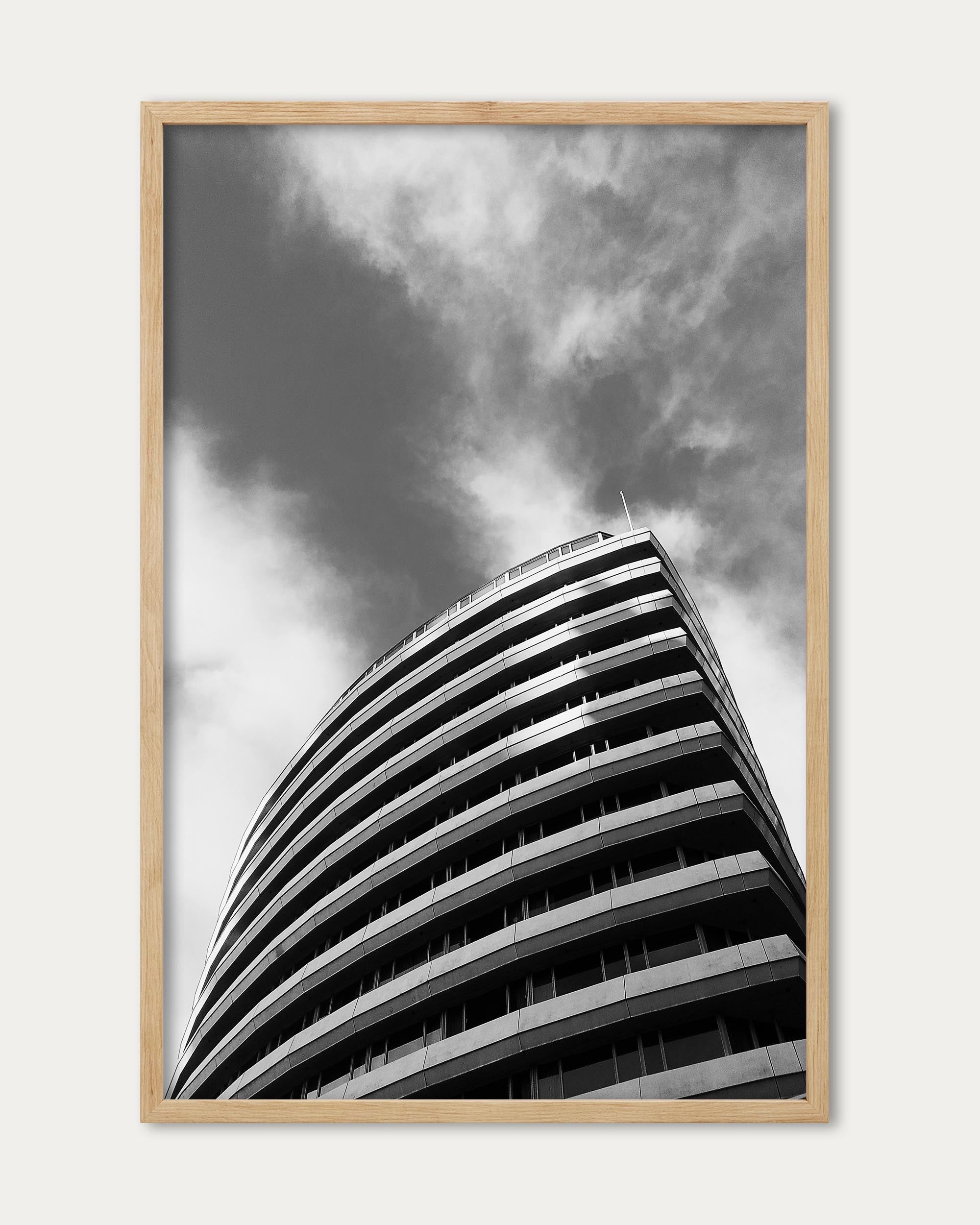 Framed black and white photograph of a modern building against a cloudy sky
