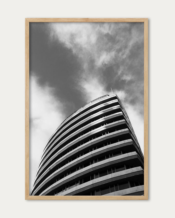 Framed black and white photograph of a modern building against a cloudy sky