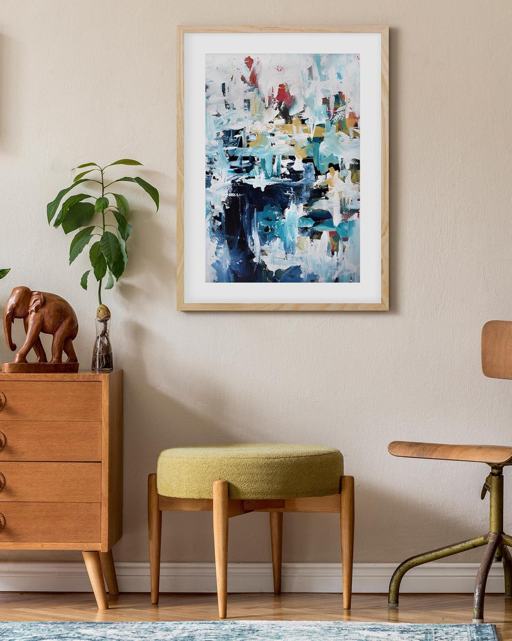 Abstract painting on a wall above a wooden cabinet with decorative items.