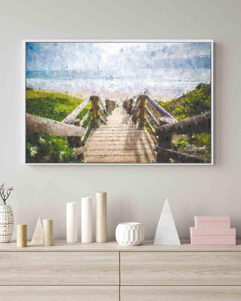 Framed artwork of a wooden bridge over water on a wall above a console table with decorative items.