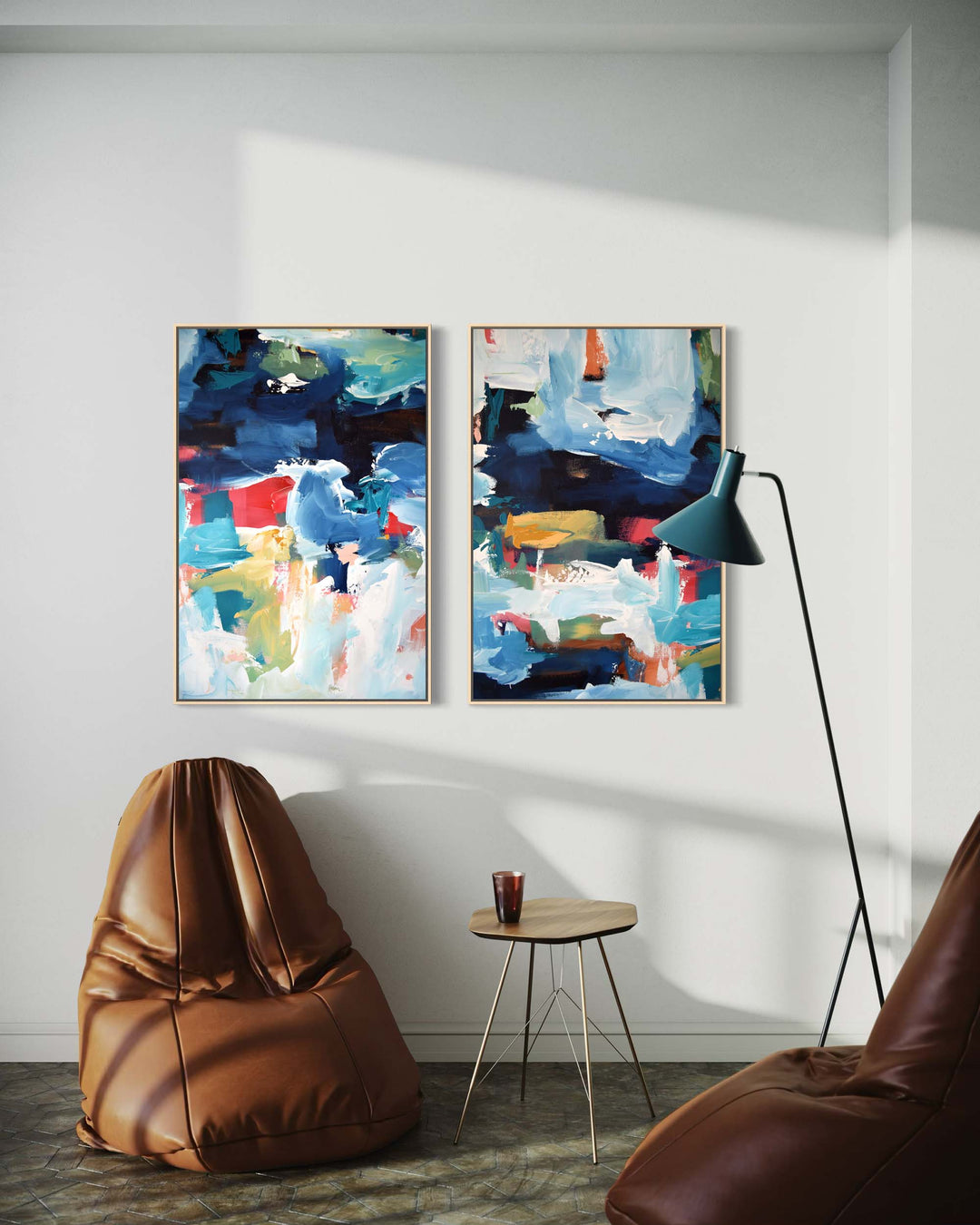 Two abstract paintings on a wall with a brown bean bag chair and a lamp in a room.