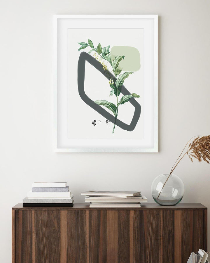 Framed artwork with a geometric design and plant elements on a wall above a wooden cabinet.