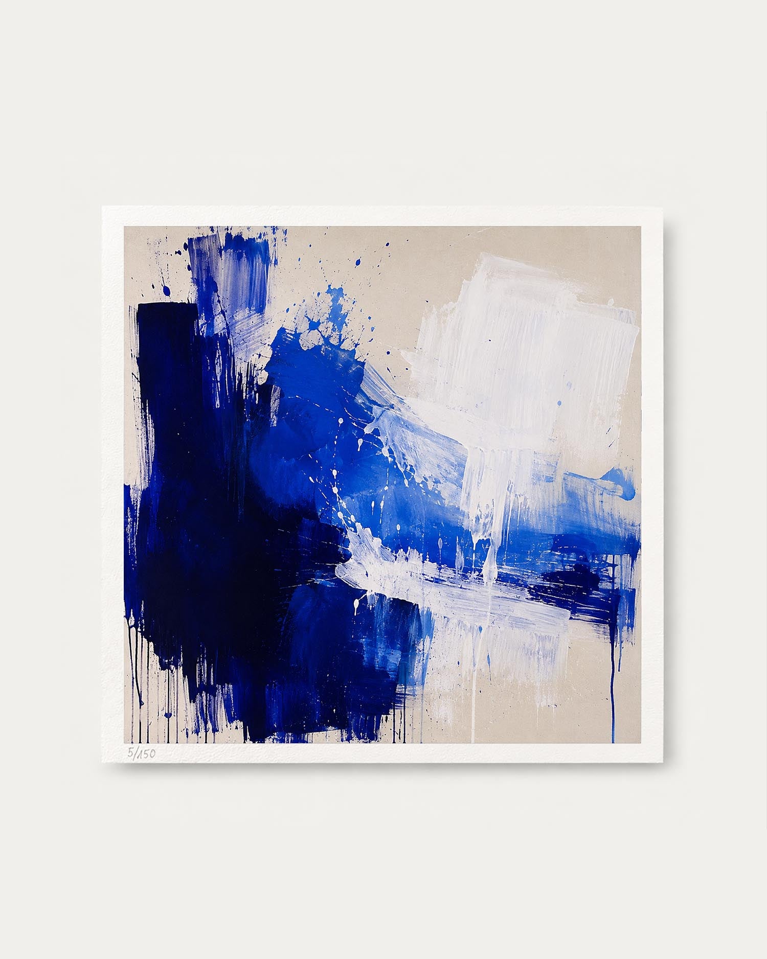 An abstract square canvas painting featuring bold blue and white brushstrokes on a warm beige background, presented with a white border against a light gray wall.
