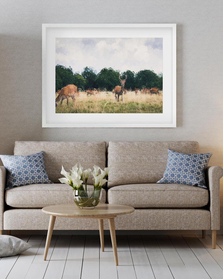 Framed photograph of deer in a field above a beige sofa with decorative pillows.