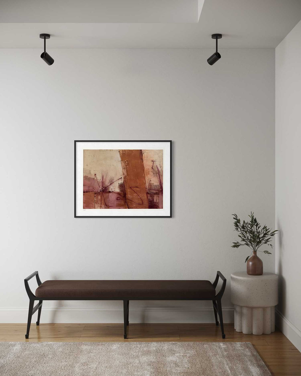 A framed abstract art print with earthy brown, terracotta, and beige tones, displayed on a light gray wall above a dark brown bench in a modern room setting.