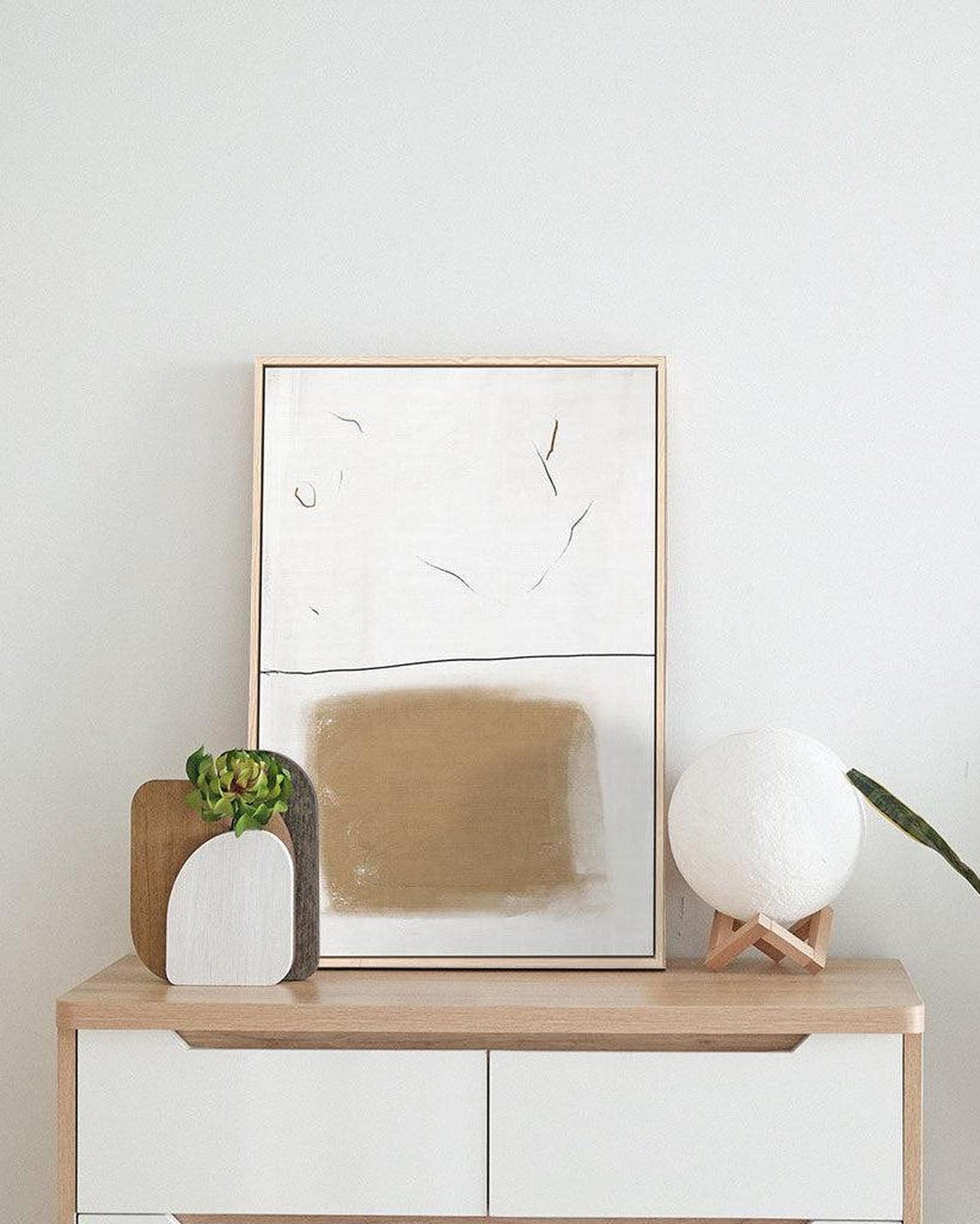 Modern interior with a wooden console table, abstract art, and decorative items.