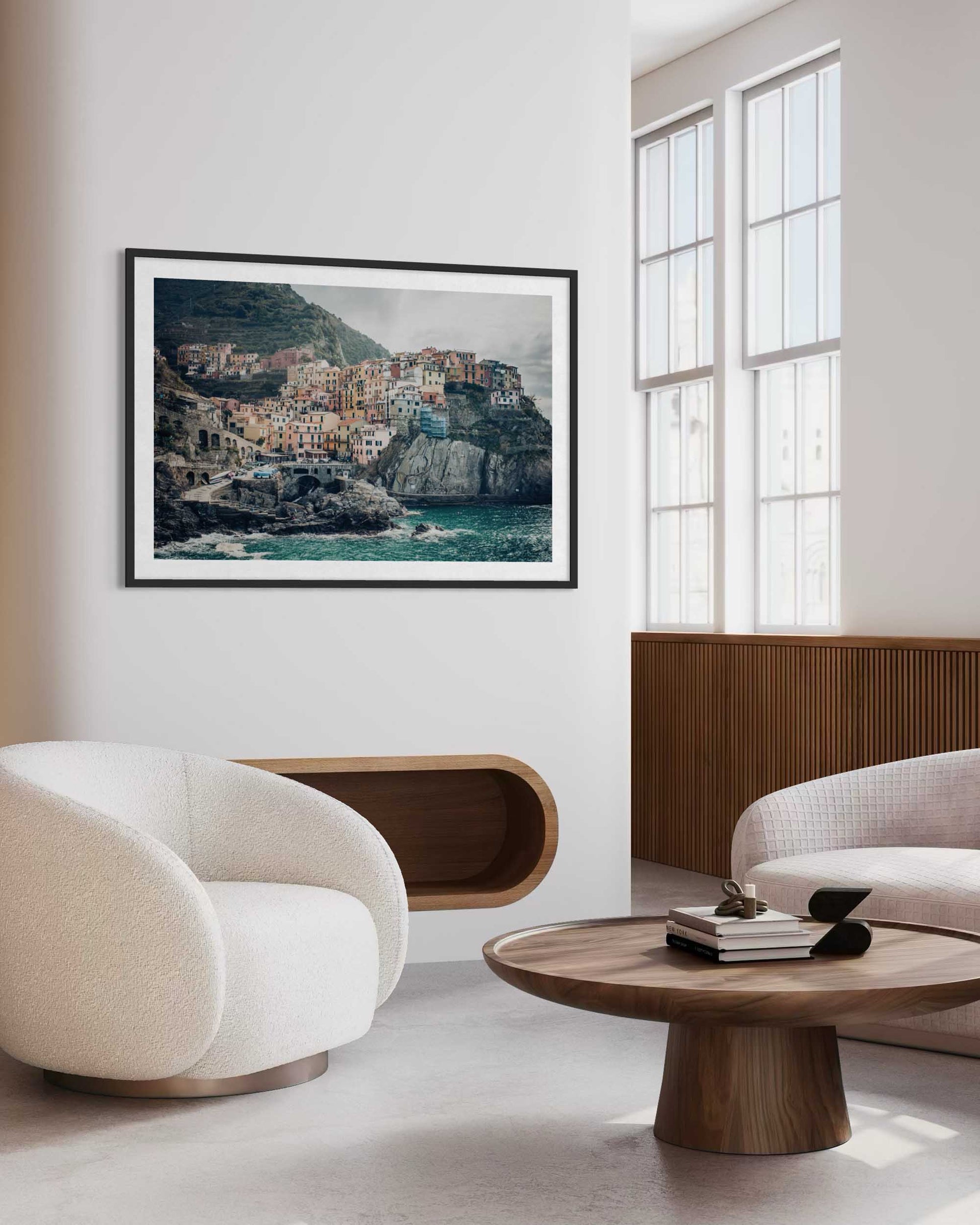 Modern living room with white chairs, a wooden coffee table, and a large framed photograph on the wall.