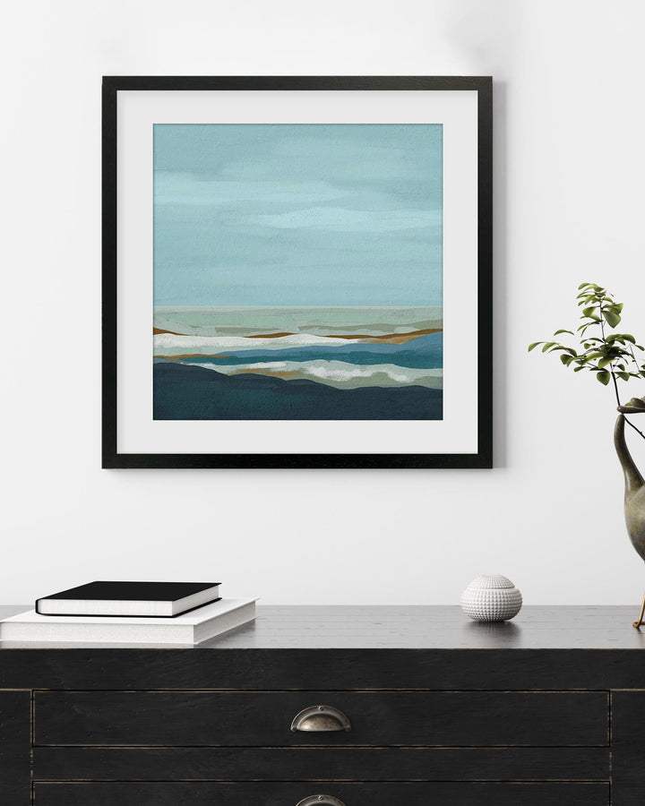 Framed abstract art piece on a wall above a black dresser with decor items.