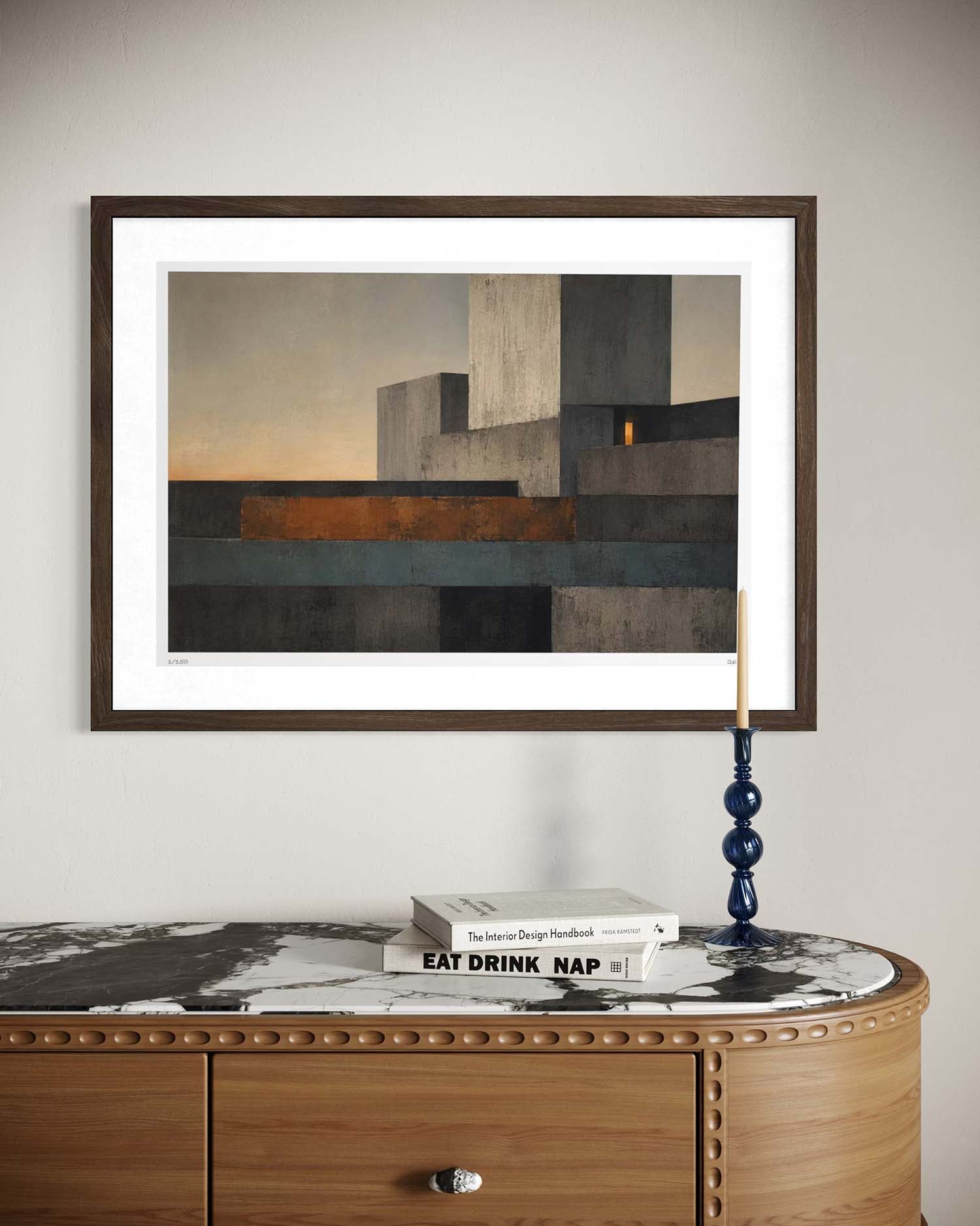 A framed abstract geometric art print with a white mat and dark wood frame, displayed on a light gray wall above a wooden console table with a marble top.