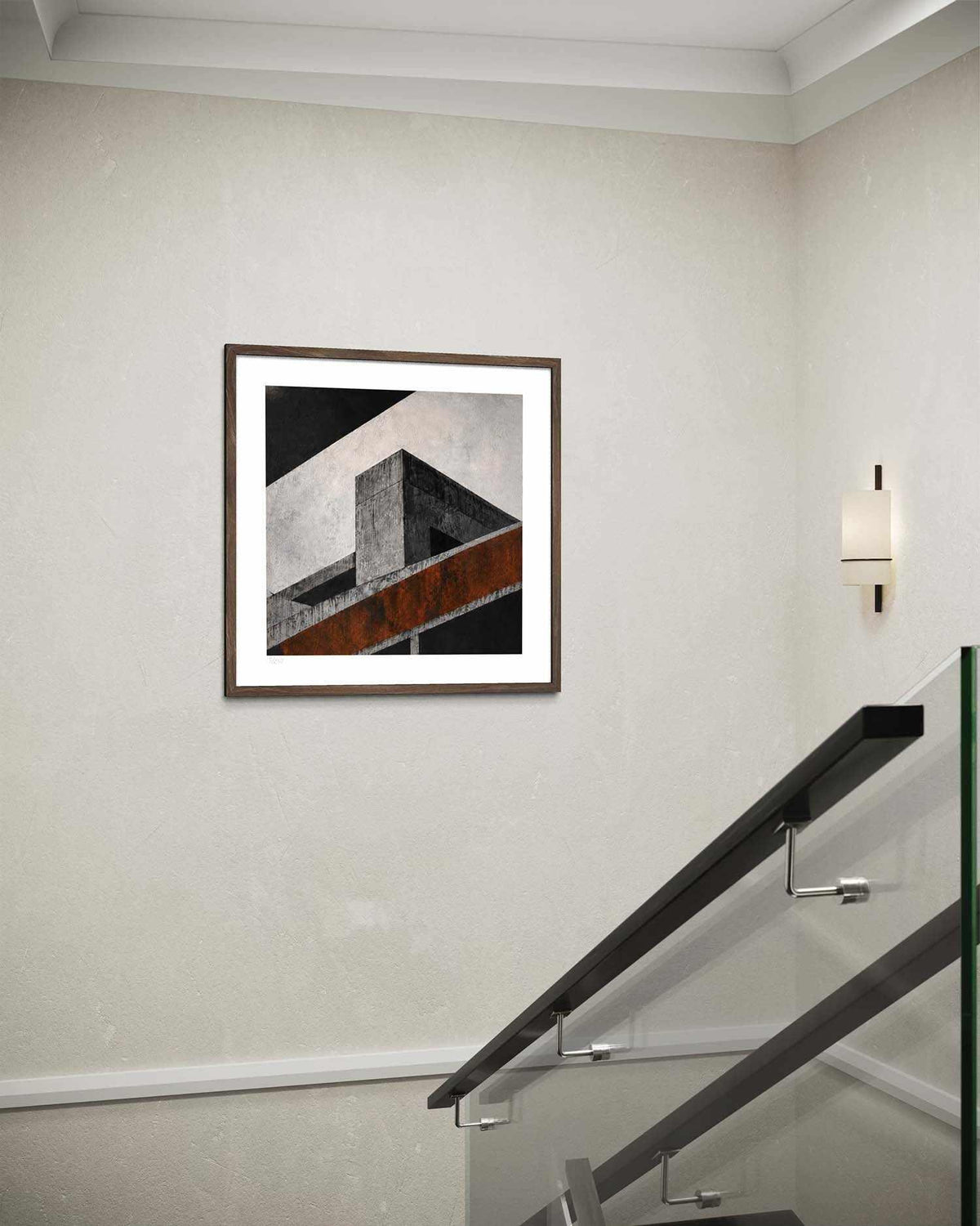 A framed abstract geometric wall art print hanging on a textured off-white wall above a modern glass railing staircase.