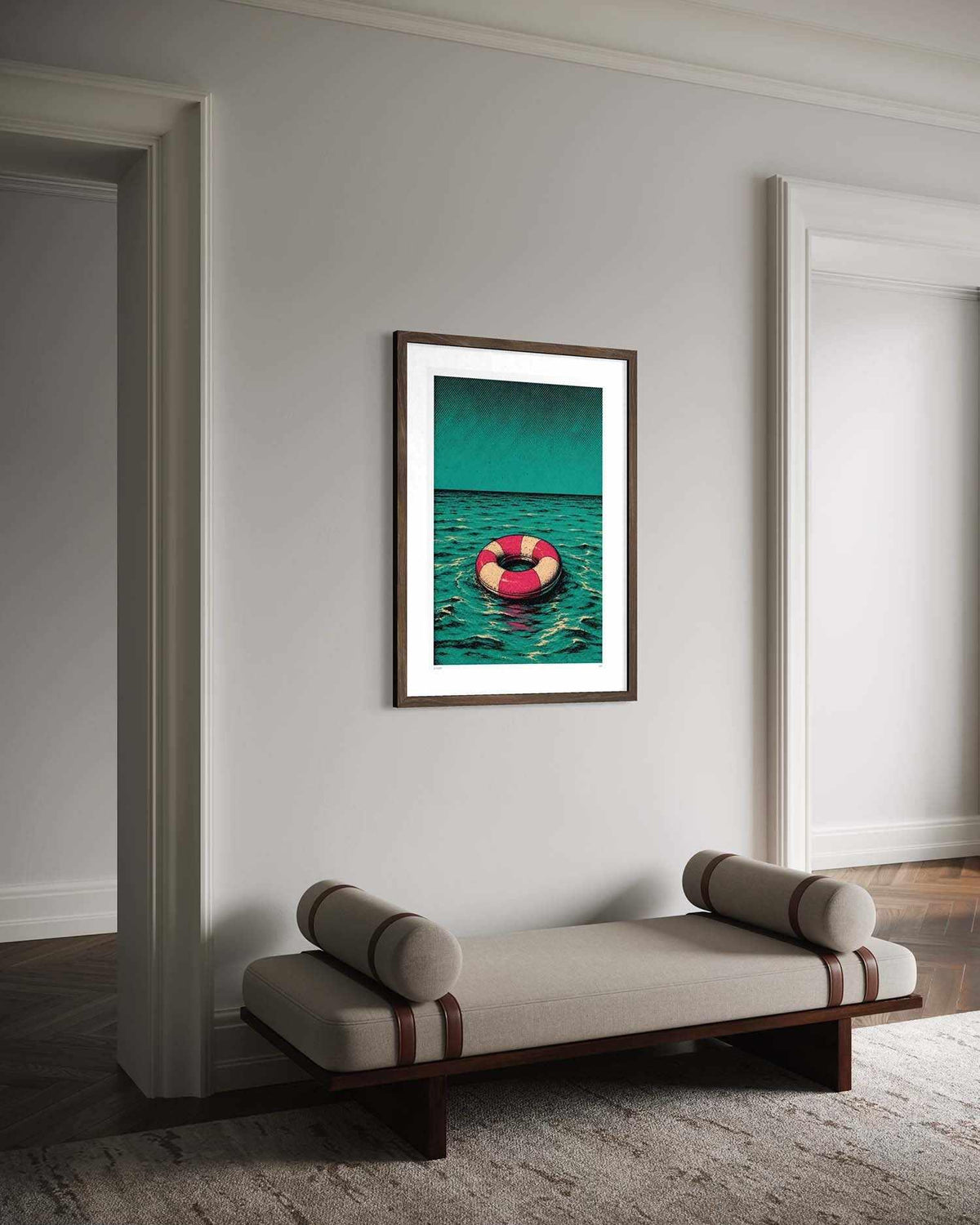 A framed art print featuring a pink and black life preserver floating on teal water, displayed on a light gray wall above a modern beige bench in a minimalist room.