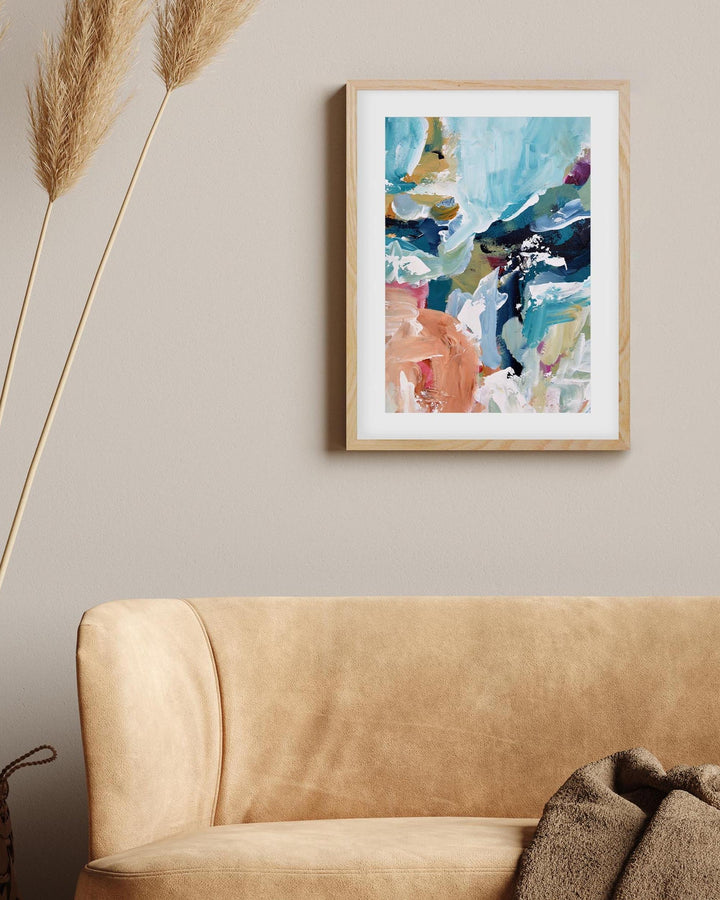 Framed abstract art on a wall above a beige sofa with decorative elements.
