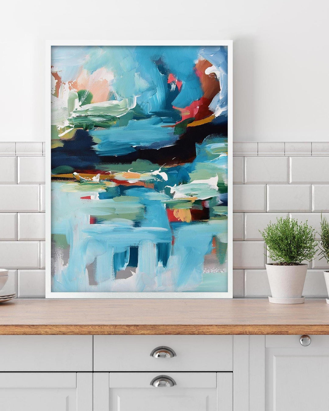 Abstract painting on a wall above a wooden cabinet with plants.