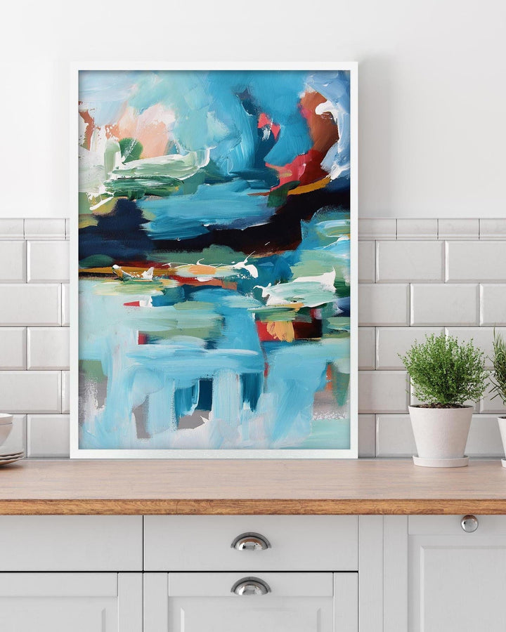 Abstract painting on a wall above a wooden cabinet with plants.