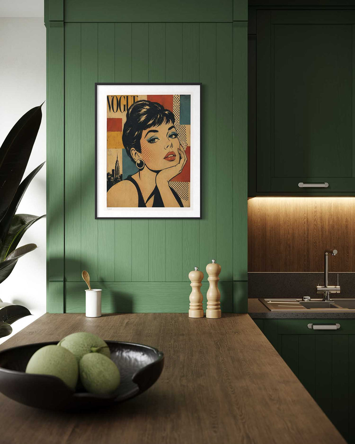 A framed art print featuring a stylized portrait of Audrey Hepburn from Vogue Paris, displayed on a dark green paneled wall in a modern kitchen setting.
