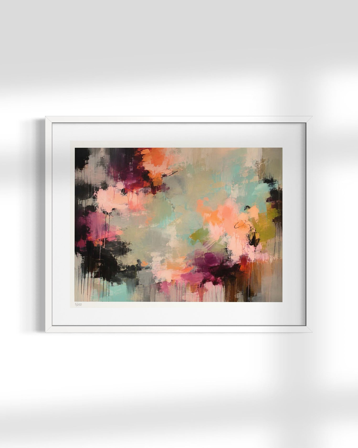 A framed abstract art print featuring a colorful paint splatter design in shades of pink, orange, purple, teal, and brown, presented in a white frame against a light gray wall.