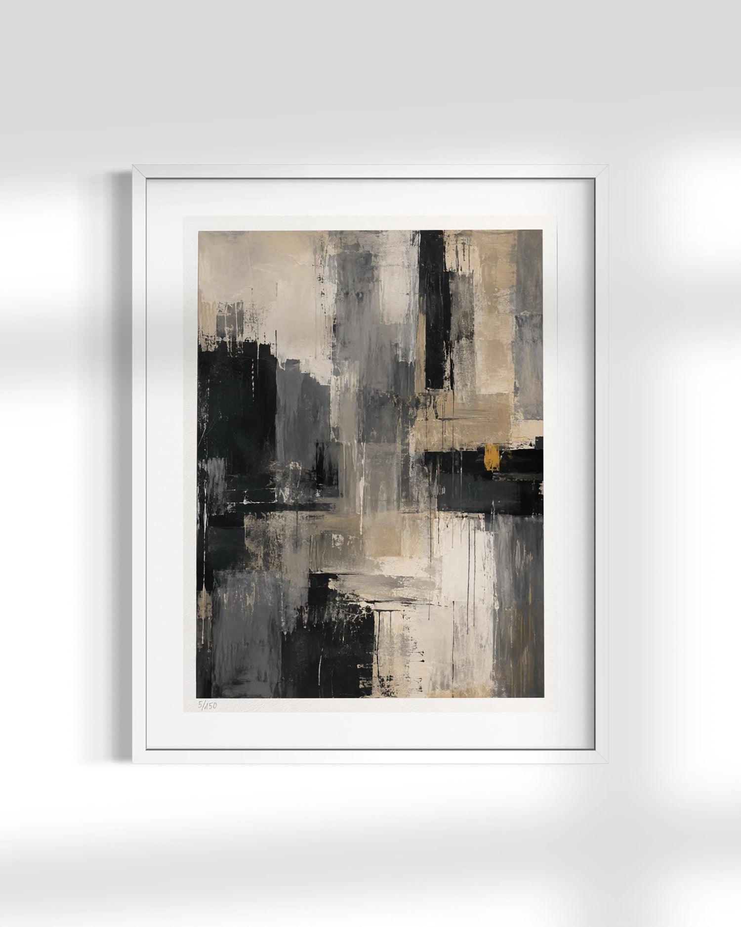 A framed abstract art print featuring textured brushstrokes in black, gray, beige, and white, with a small touch of gold, displayed on a light gray wall.