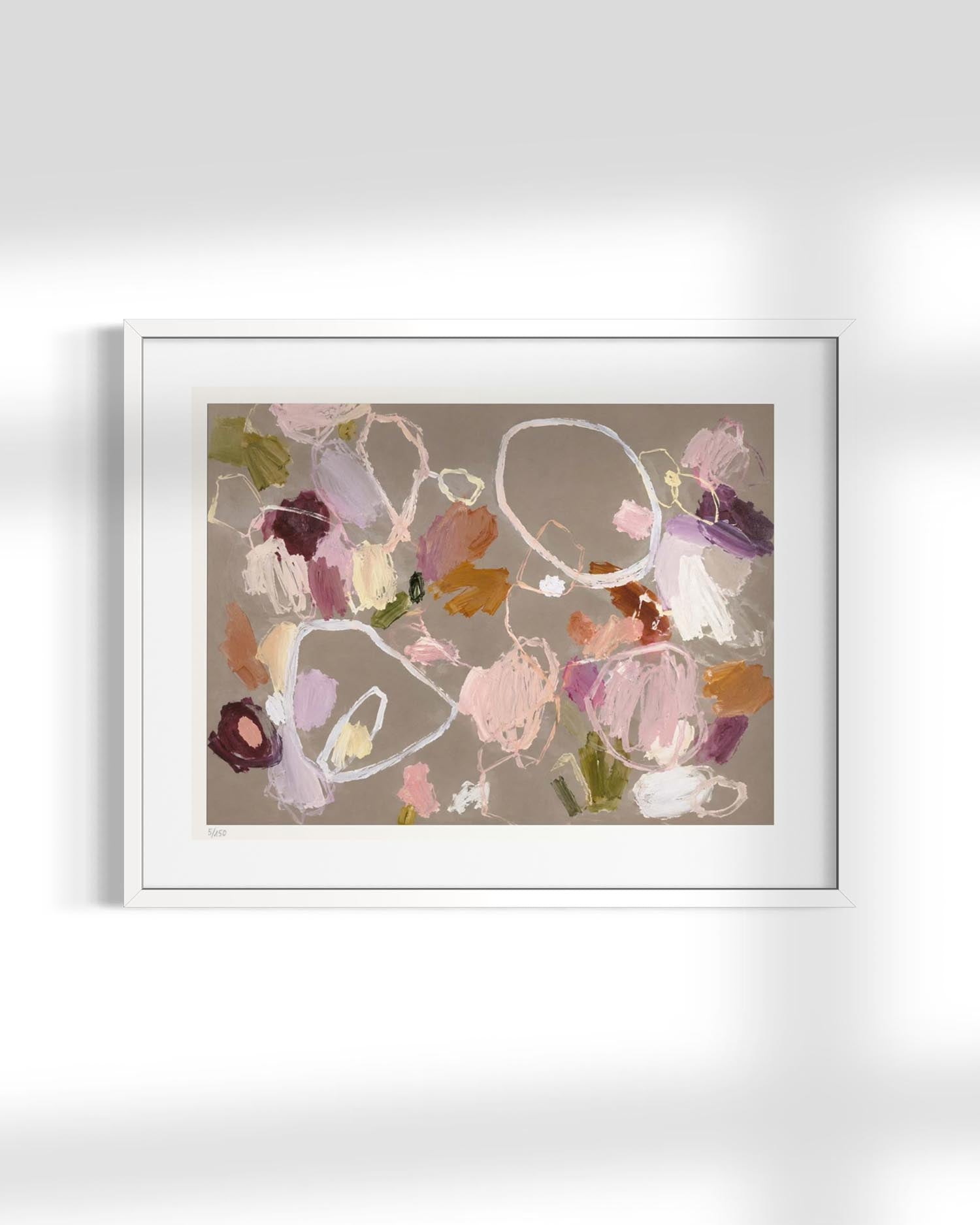 A framed abstract art print featuring expressive brushstrokes in soft pink, purple, brown, and white on a warm taupe background, presented in a white frame against a light gray wall with soft shadows.