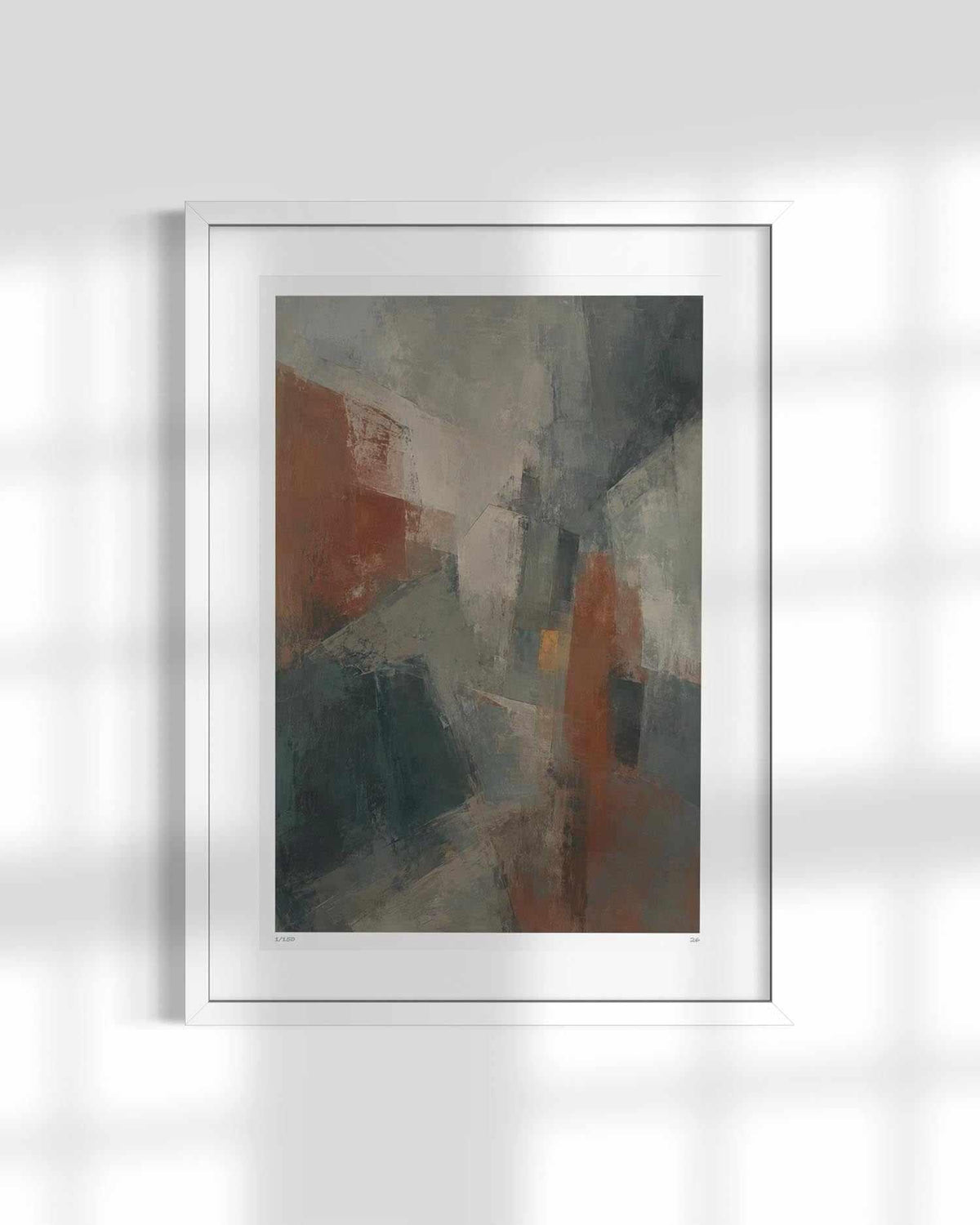 A framed abstract art print featuring a mix of gray, brown, and rust-orange brushstrokes, displayed in a white frame against a light gray wall with soft window shadow patterns.