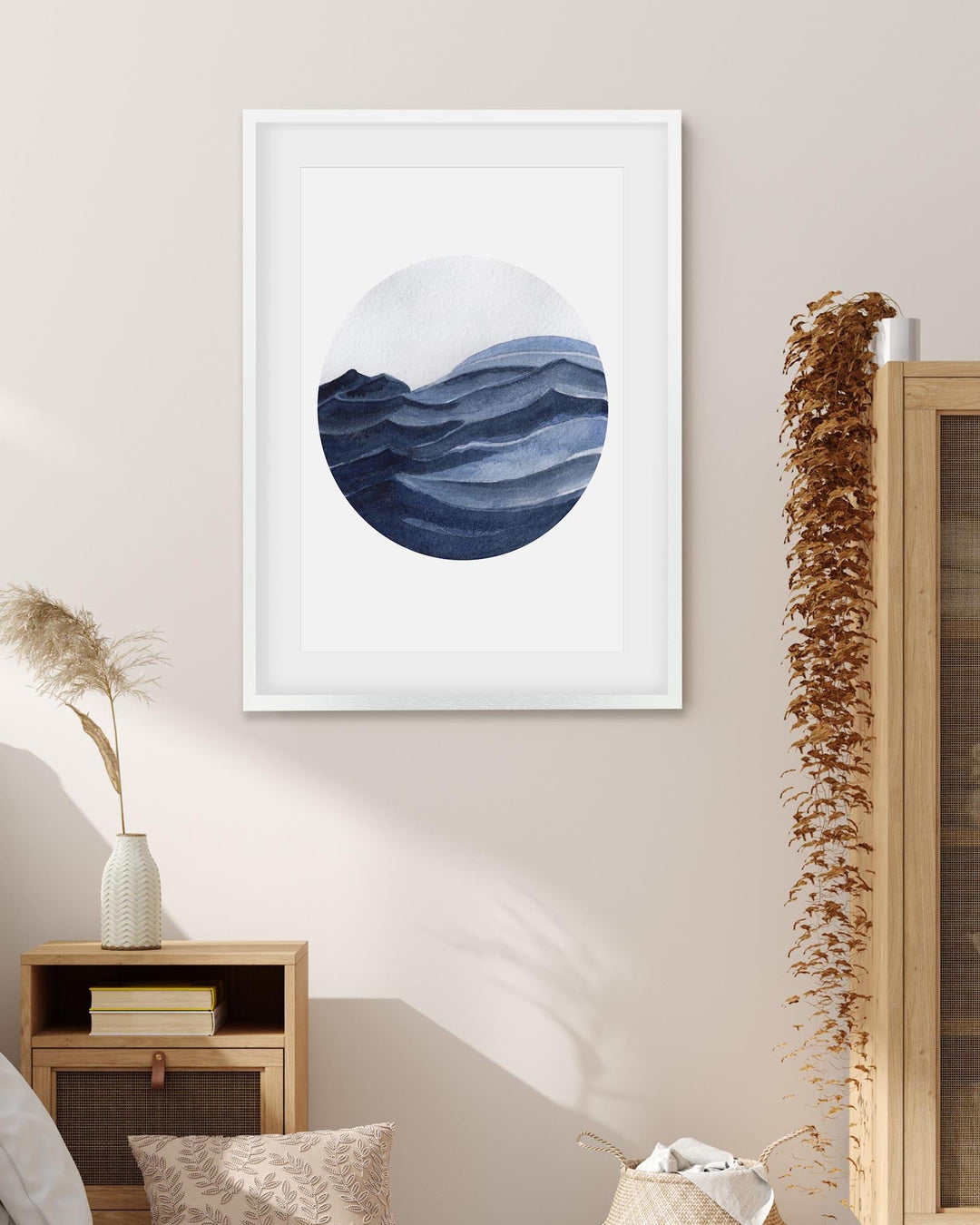 Framed abstract art of wavy blue design on a wall above a wooden cabinet.