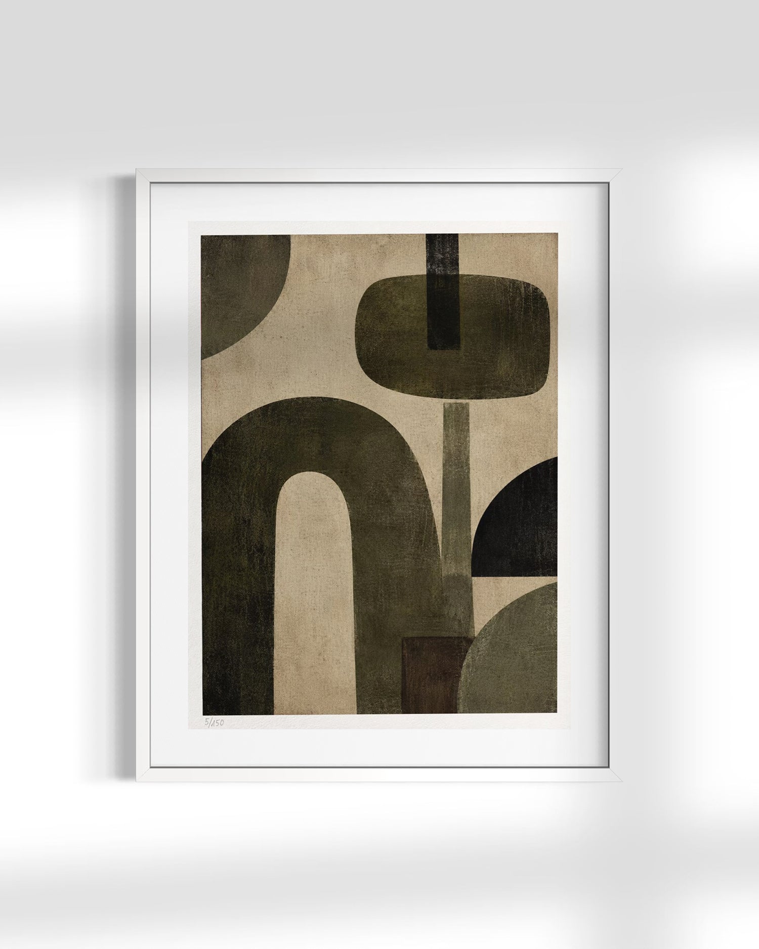A framed abstract art print featuring organic geometric shapes in dark olive green, black, and beige tones, presented in a white frame against a light gray wall with soft shadows.