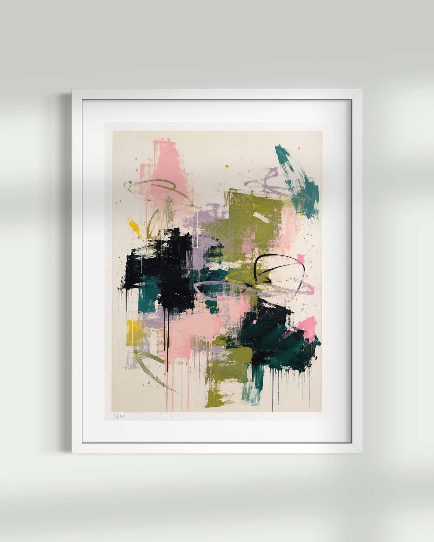 A framed abstract art print featuring expressive brushstrokes and splatters in pink, green, black, purple, and teal on a warm cream background, displayed against a light gray wall.