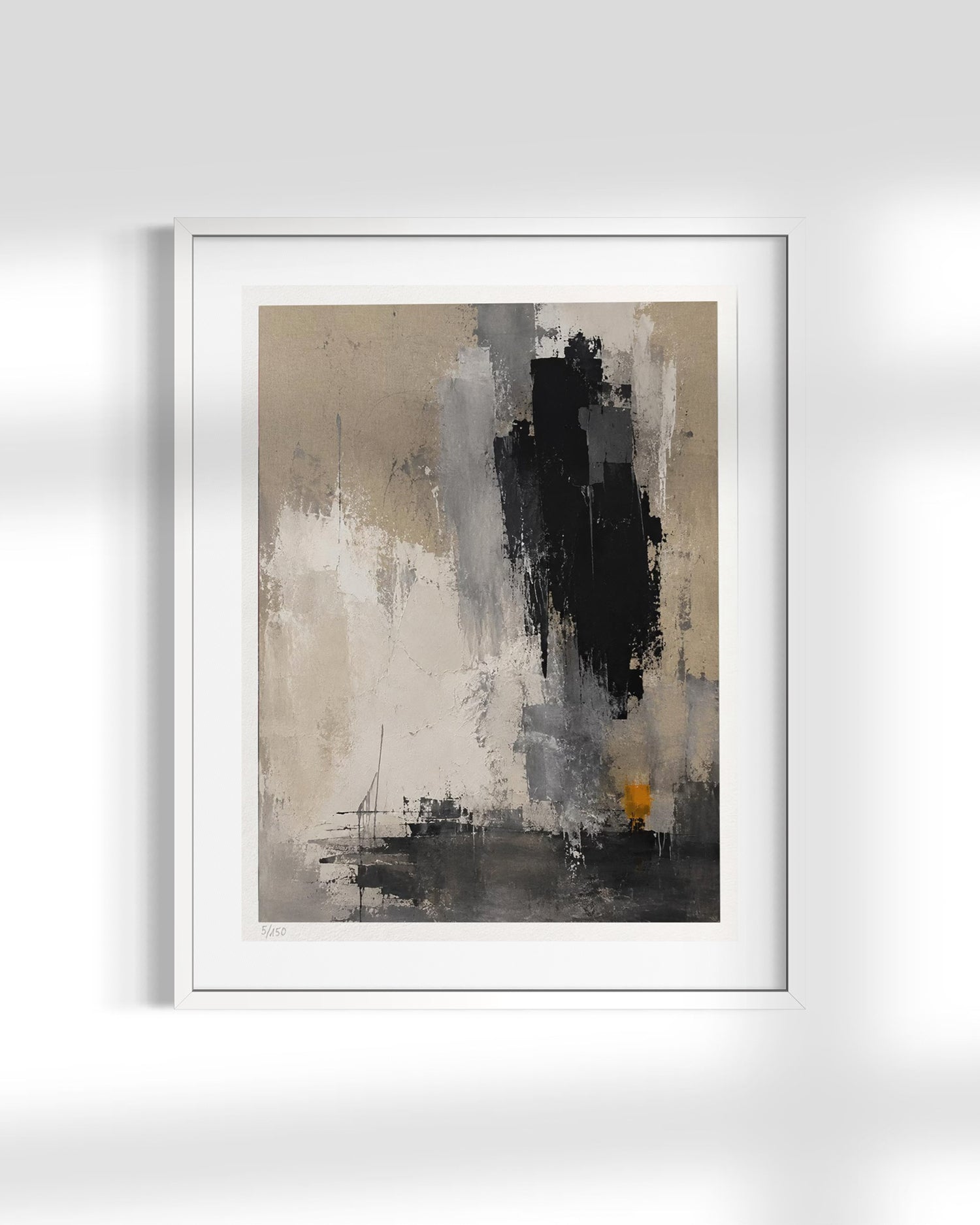 A framed abstract art print featuring textured brushstrokes in black, gray, beige, and white, with a small touch of yellow near the bottom right. The print is housed in a white frame and displayed against a light gray wall with soft shadow overlays.