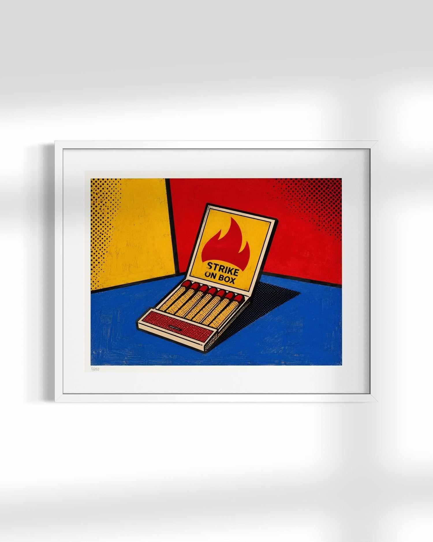 A framed pop-art print of a matchbox on a bold red, yellow, and blue background, displayed on a light gray wall.