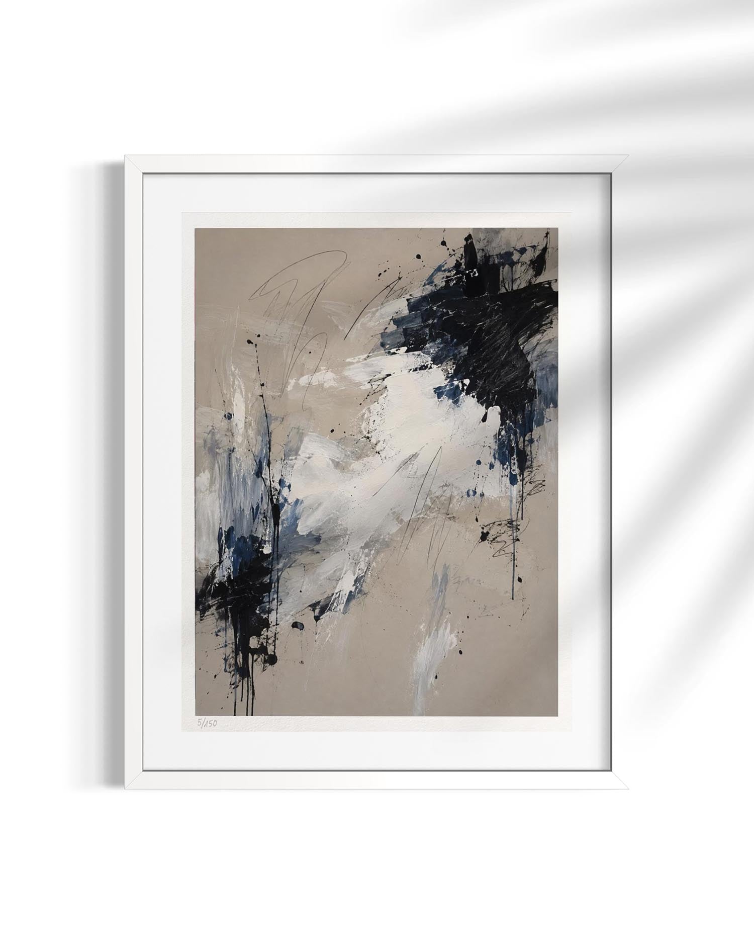 A framed abstract art print featuring black, white, and blue paint splatters on a beige background, presented in a white frame against a white wall with soft shadow overlays.