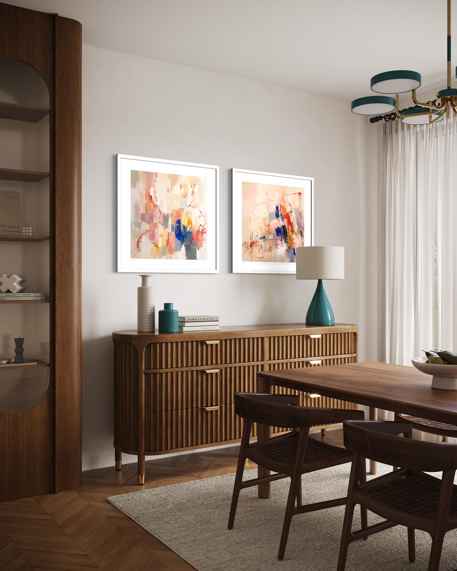 A styled dining room featuring two framed abstract art prints with white frames, hung above a mid-century modern wooden credenza. The room includes a wooden dining table and chairs, a teal ceramic table lamp, and a tall wooden shelving unit on the left.