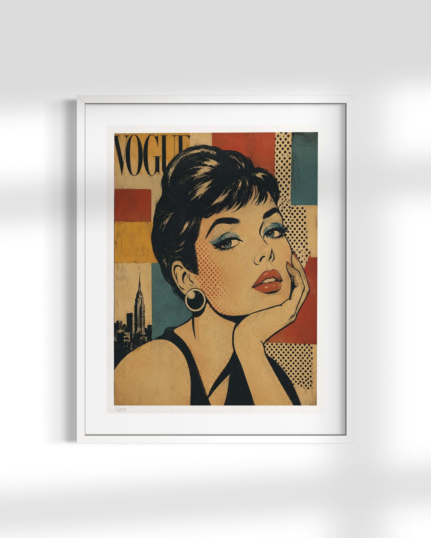 A framed art print featuring a stylized pop-art portrait of Audrey Hepburn with the word 'VOGUE' in the background, displayed on a light gray wall with soft shadows.
