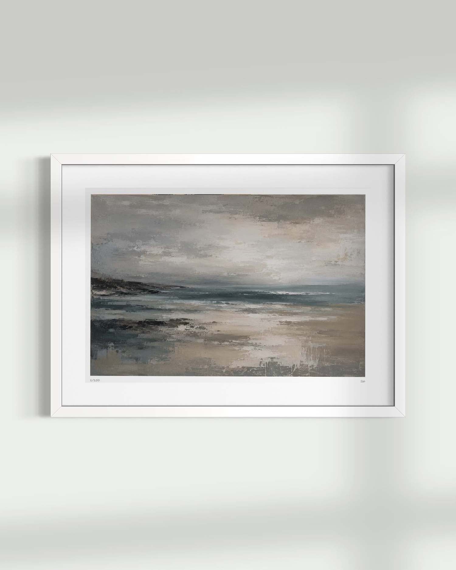 A framed landscape painting of a misty beach or shoreline under a cloudy sky, shown hanging on a light gray wall with soft shadows.