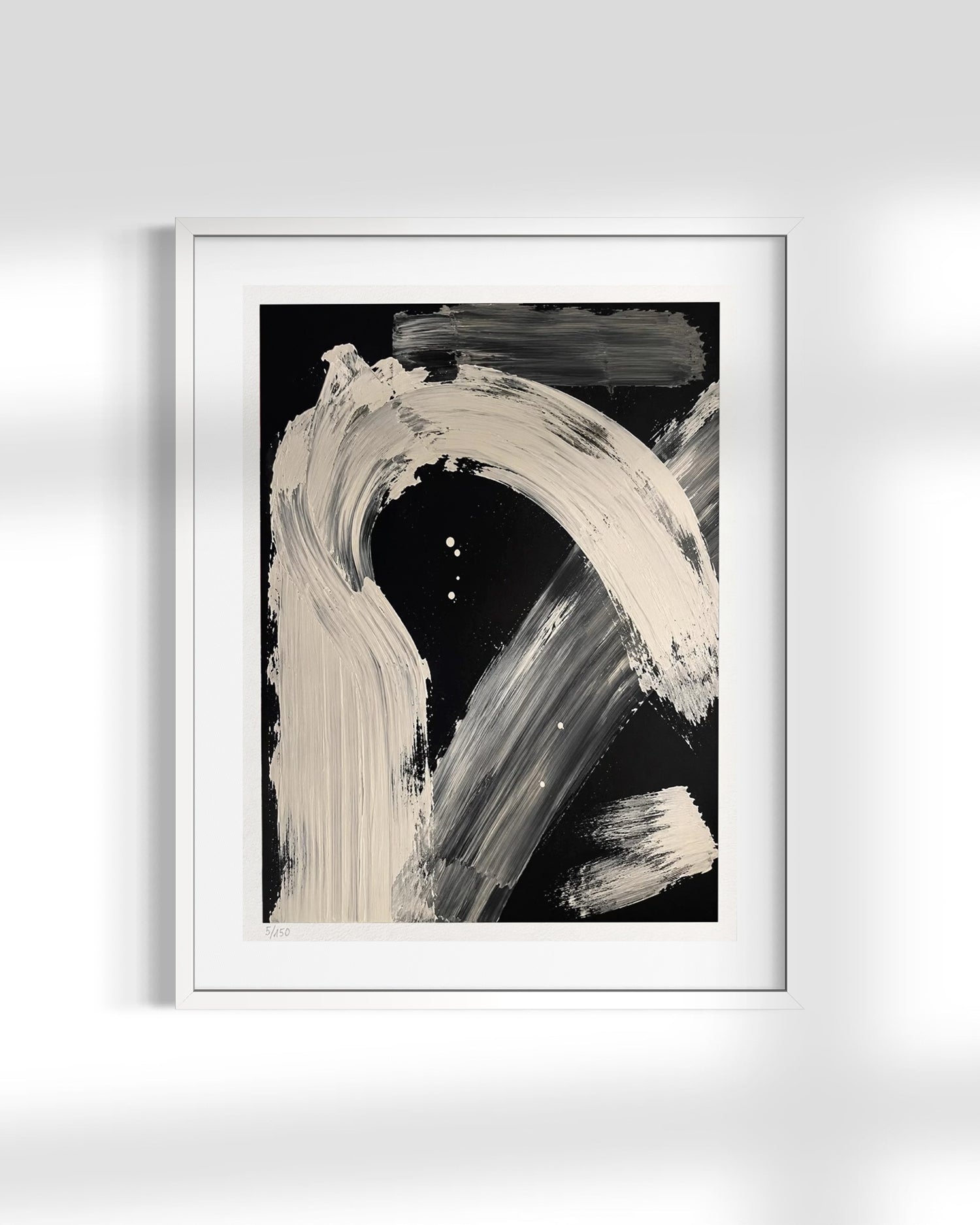 A framed abstract art print featuring bold, sweeping beige and gray brushstrokes on a black background, presented in a white frame against a light gray wall with soft shadows.